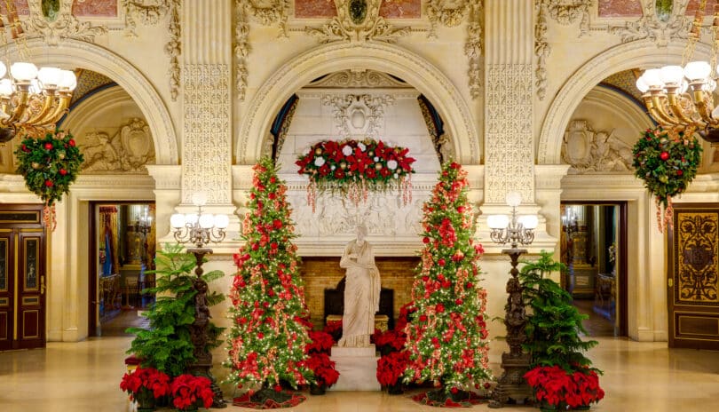 An ornate lobby in a Newport RI hotel with Christmas decorations, featuring poinsettias and garlands around a central statue.