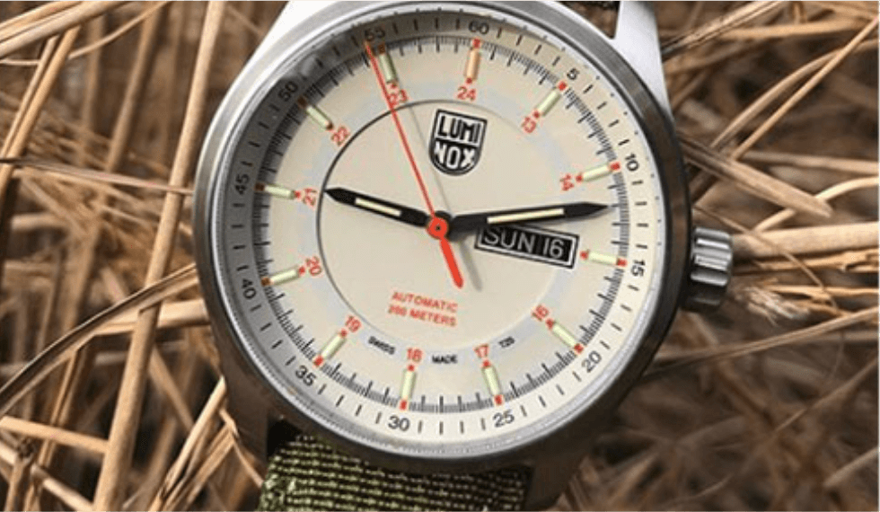 A close-up of a Luminox automatic watch displaying a date of Sunday the 16th, set against a background of dry grass near one of the hotels in Newport RI.