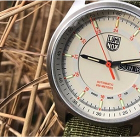Close-up of a Luminox wristwatch displaying the date and time, set against a natural background of dried grass near Newport RI hotels.
