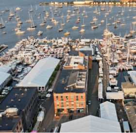 Aerial view of a busy marina with densely packed boats and adjacent buildings, highlighting a distinctive orange hotel in Newport RI.