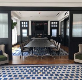 Elegant dining room in a Newport RI hotel with a long table, patterned blue tile floor, dark wood paneling, and large windows.