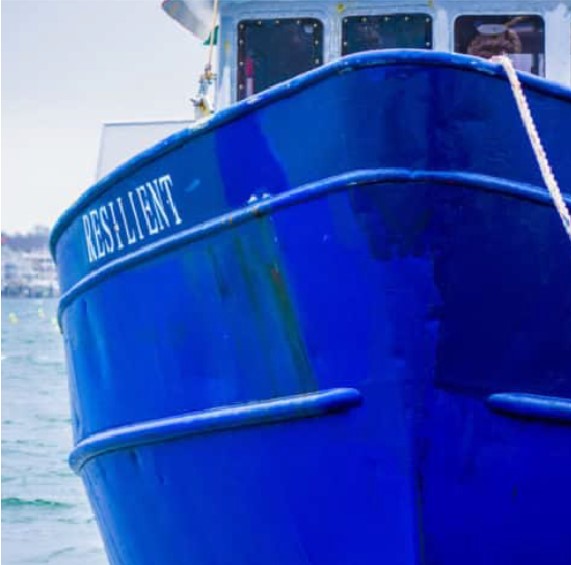 A blue boat labeled "resilient" moored on a body of water near Newport, RI, with a focus on its bow and the visible rope tied at the front.