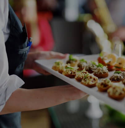 A caterer holding a tray of assorted gourmet appetizers at a Newport RI hotel event.