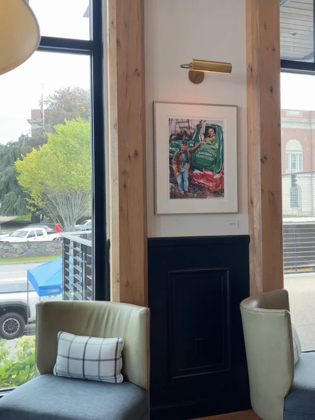 A cozy lounge area with a window, two chairs, and a piece of artwork on the wall.